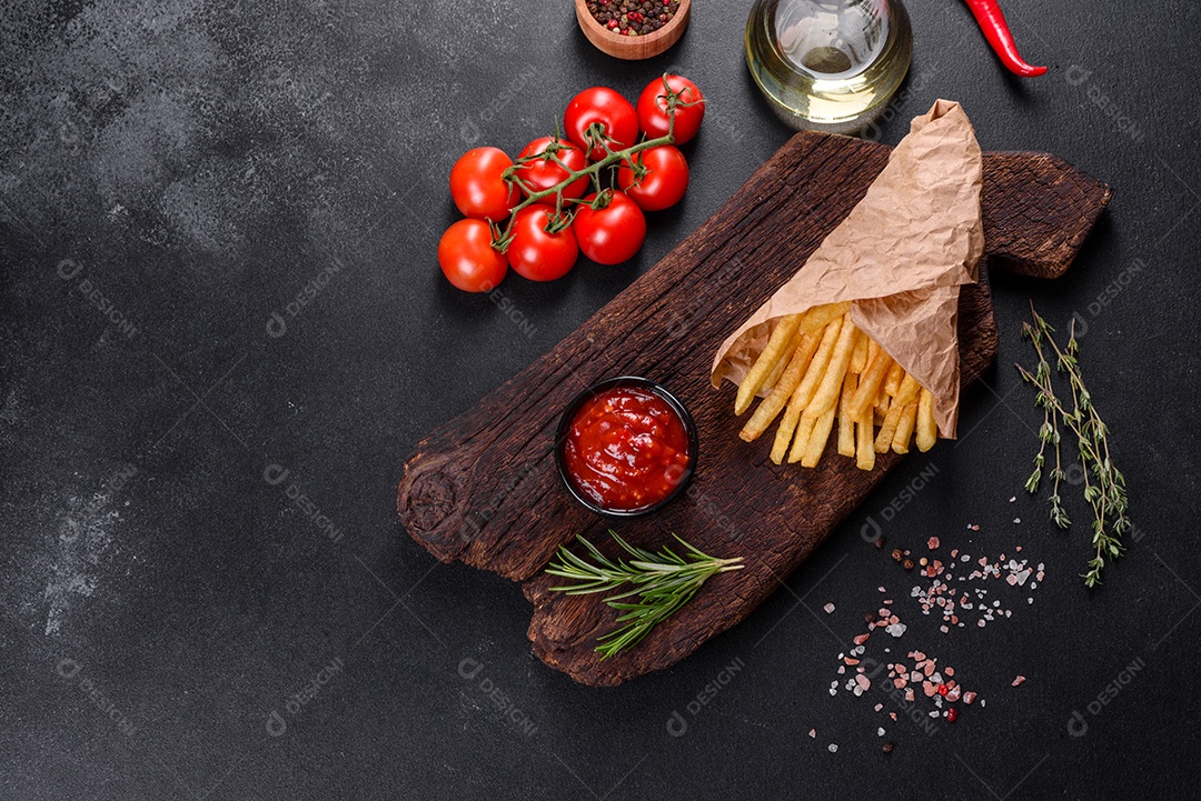 Frescas saborosas batatas fritas e molho vermelho em uma tábua de madeira. Alimentos não saudáveis