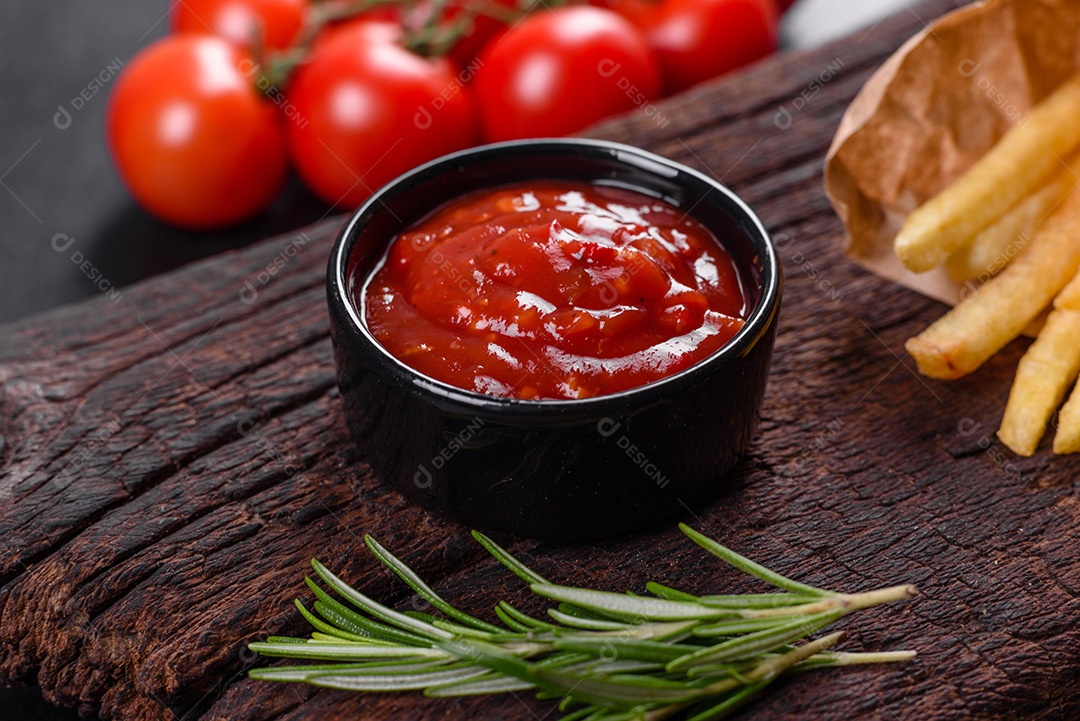 Frescas saborosas batatas fritas e molho vermelho em uma tábua de madeira. Alimentos não saudáveis