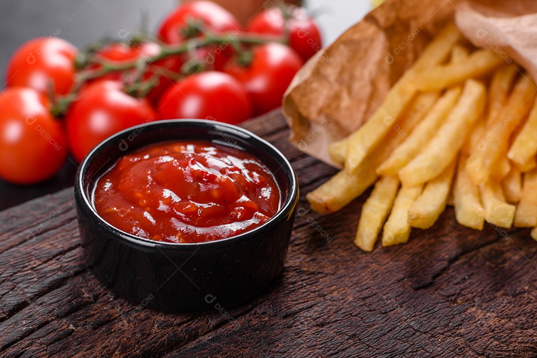 Frescas saborosas batatas fritas e molho vermelho em uma tábua de madeira. Alimentos não saudáveis