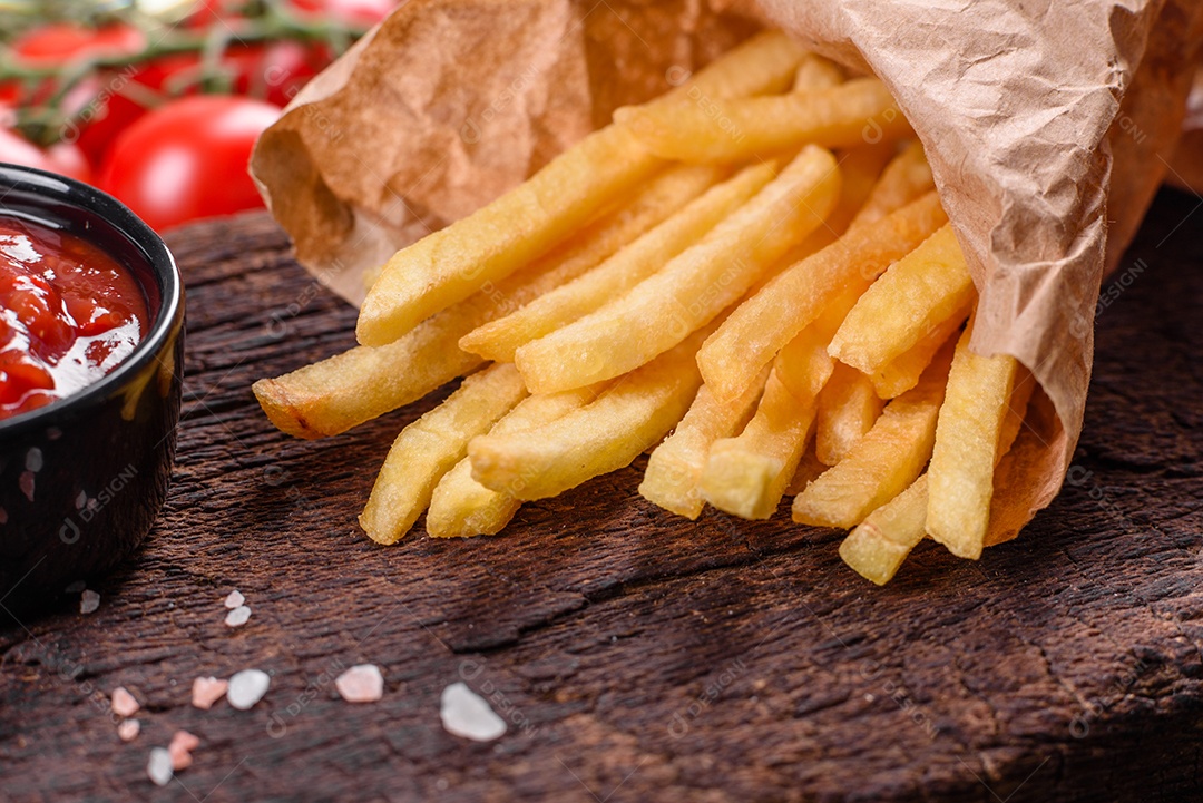 Frescas saborosas batatas fritas e molho vermelho em uma tábua de madeira. Alimentos não saudáveis