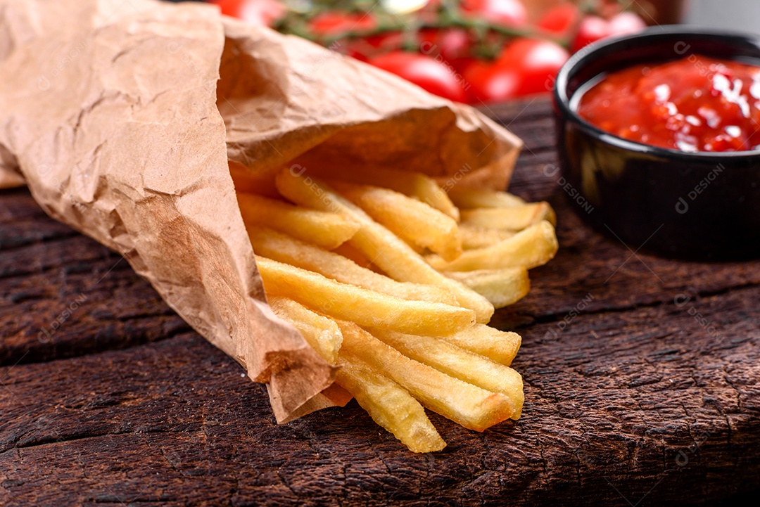 Frescas saborosas batatas fritas e molho vermelho em uma tábua de madeira. Alimentos não saudáveis