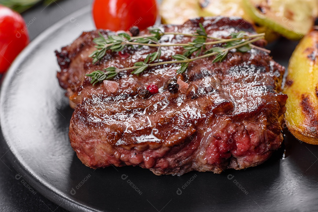 Bife fresco, suculento e delicioso em um fundo escuro. Prato de carne com especiarias e ervas