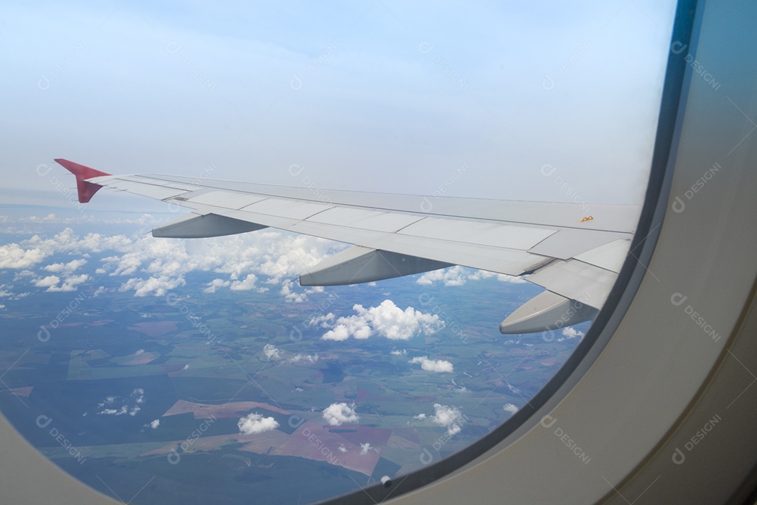Asa de um avião voando acima da cidade A vista de uma janela de avião. Céu nublado e colorido com luz solar