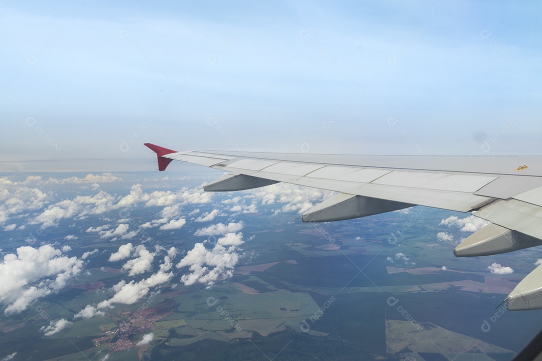 Asa de um avião voando acima da cidade A vista de uma janela de avião. Céu nublado e colorido com luz solar