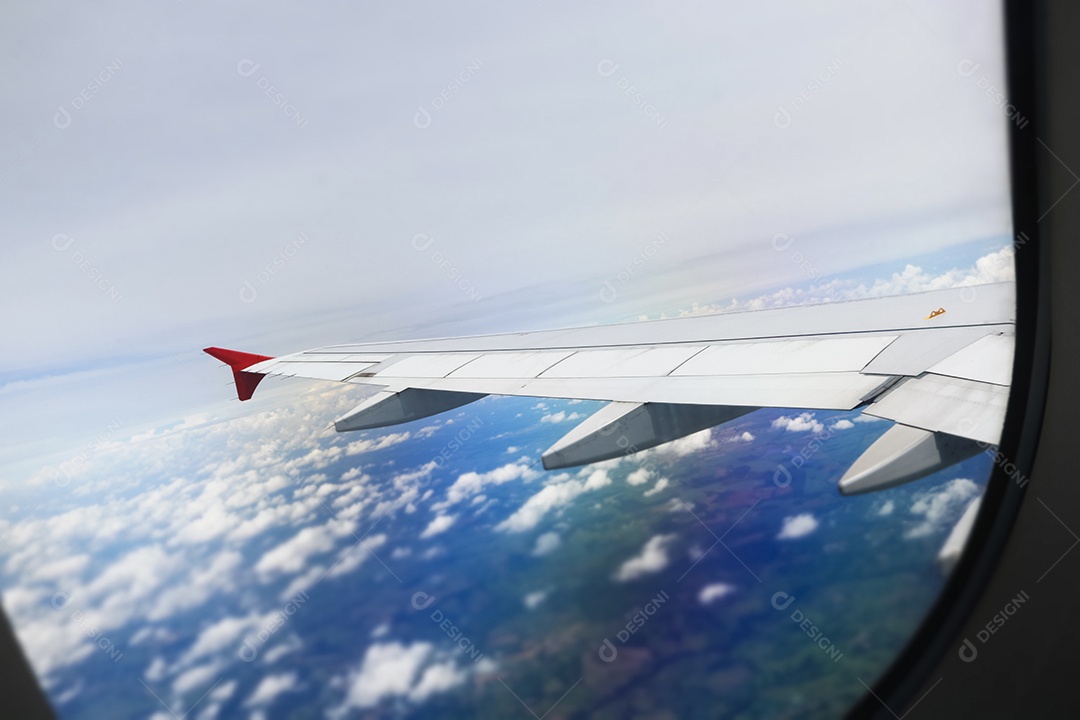 Asa de um avião voando acima da cidade A vista de uma janela de avião. Céu nublado e colorido com luz solar