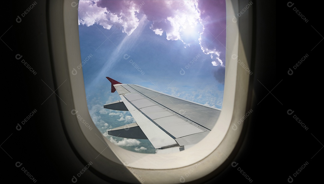 Asa de um avião voando acima da cidade A vista de uma janela de avião. Céu nublado e colorido com luz solar