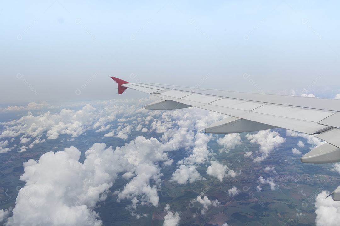 Asa de um avião voando acima da cidade A vista de uma janela de avião. Céu nublado e colorido com luz solar