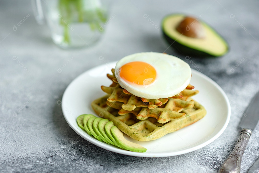 Pequeno-almoço fresco, delicioso e nutritivo com waffles com espinafre, ovo frito e pedaços de abacate