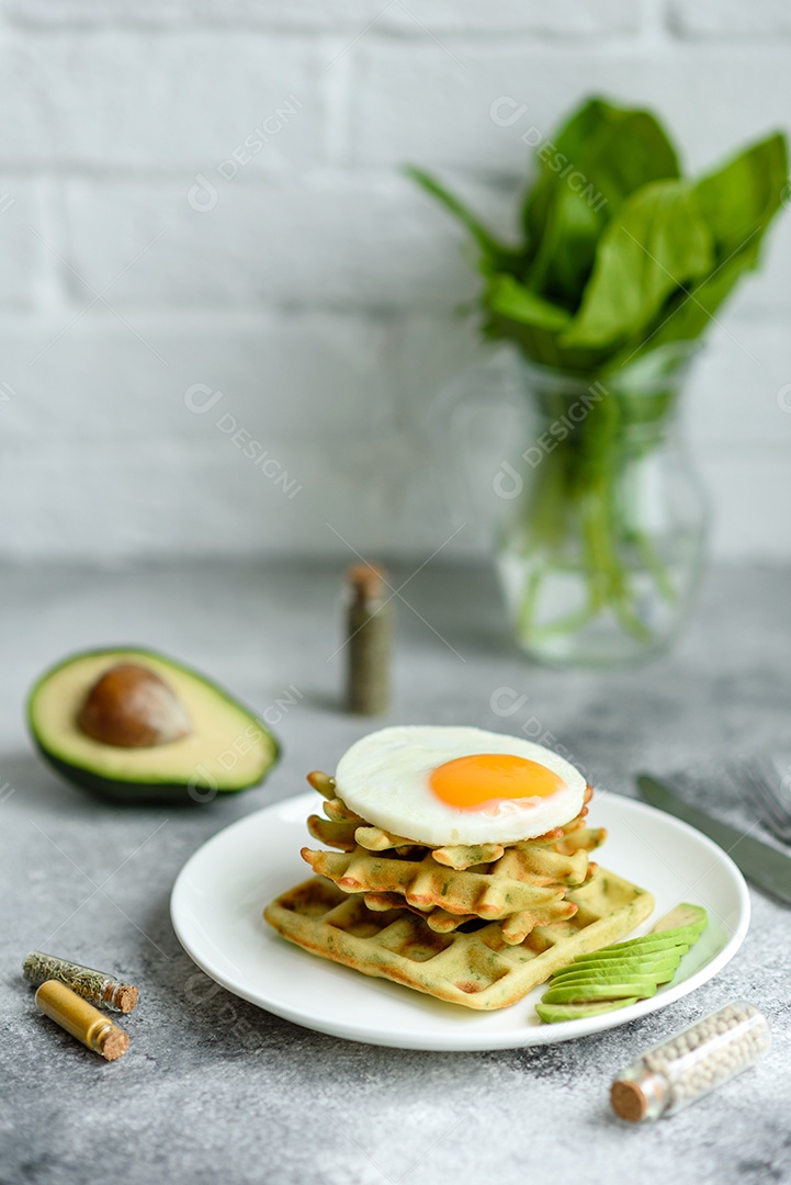 Pequeno-almoço fresco, delicioso e nutritivo com waffles com espinafre, ovo frito e pedaços de abacate