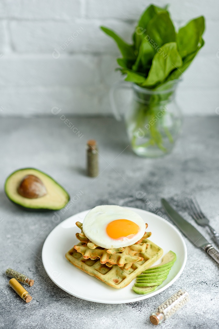 Pequeno-almoço fresco, delicioso e nutritivo com waffles com espinafre, ovo frito e pedaços de abacate