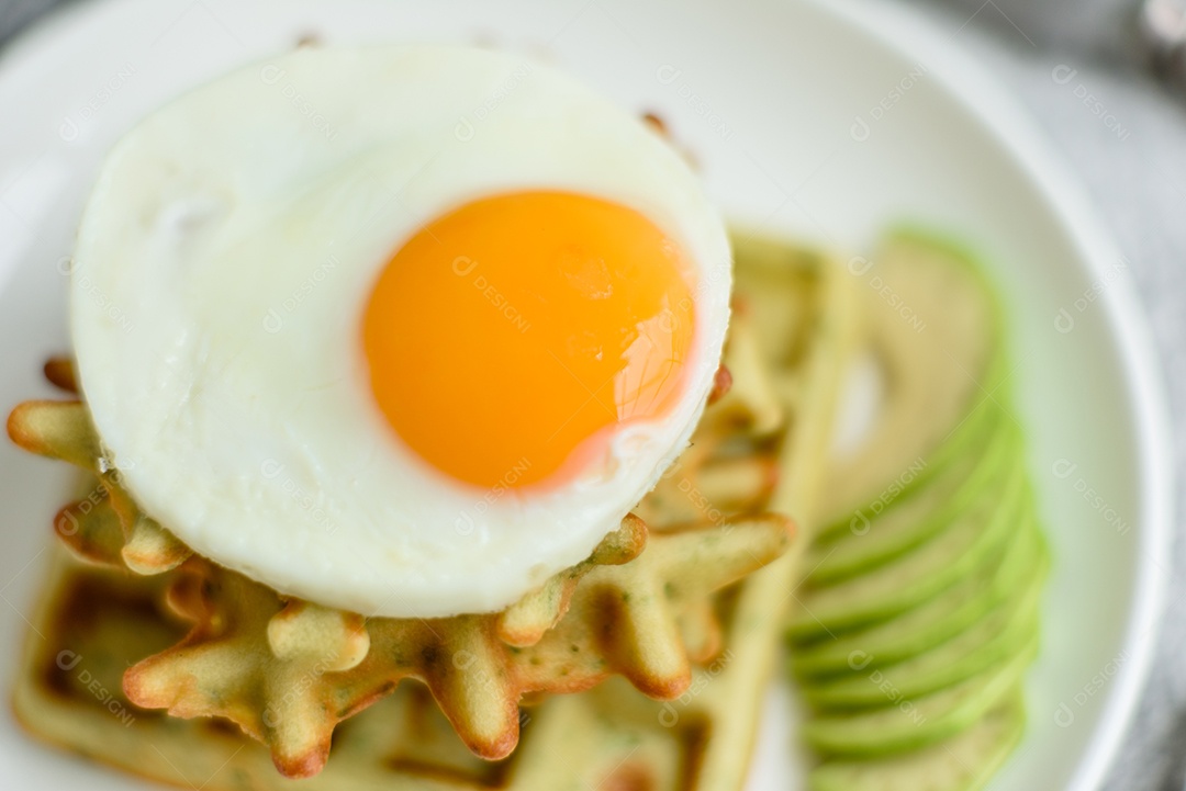 Pequeno-almoço fresco, delicioso e nutritivo com waffles com espinafre, ovo frito e pedaços de abacate