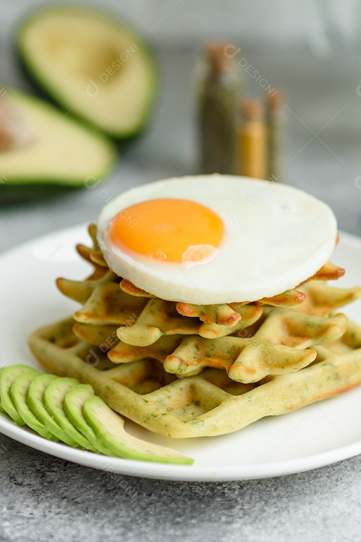 Pequeno-almoço fresco, delicioso e nutritivo com waffles com espinafre, ovo frito e pedaços de abacate
