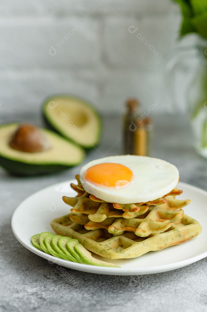 Pequeno-almoço fresco, delicioso e nutritivo com waffles com espinafre, ovo frito e pedaços de abacate