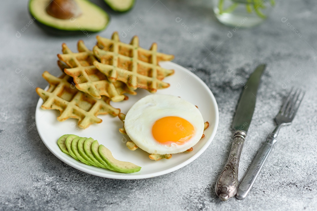 Pequeno-almoço fresco, delicioso e nutritivo com waffles com espinafre, ovo frito e pedaços de abacate