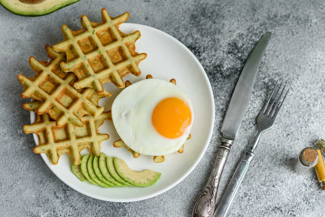 Pequeno-almoço fresco, delicioso e nutritivo com waffles com espinafre, ovo frito e pedaços de abacate
