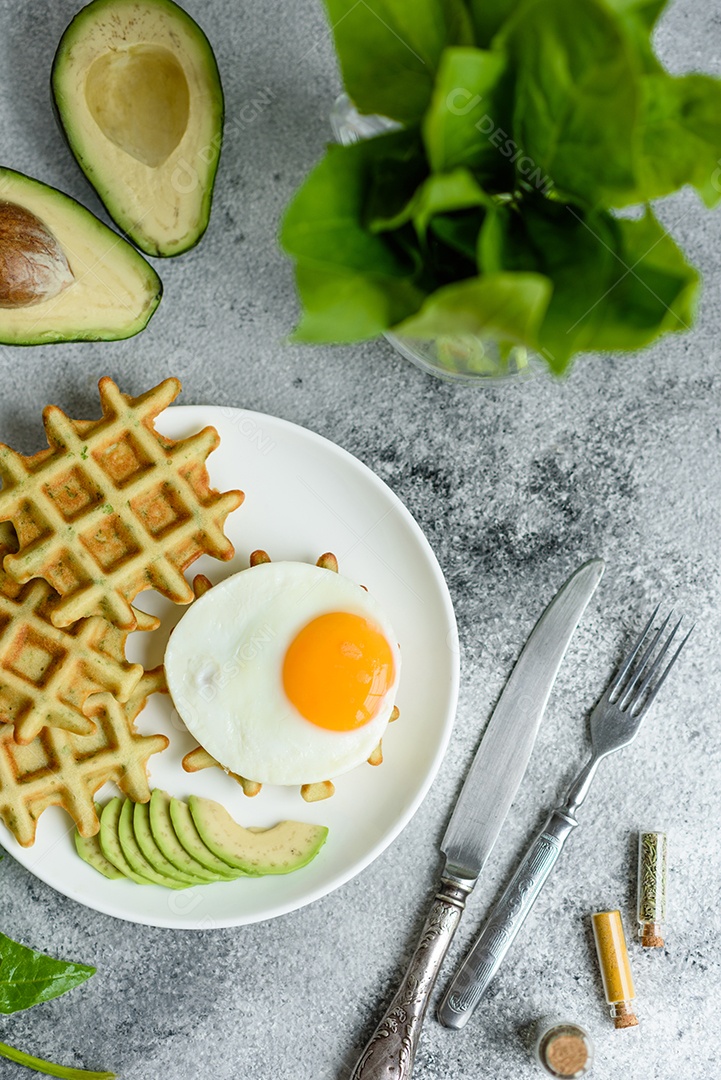Pequeno-almoço fresco, delicioso e nutritivo com waffles com espinafre, ovo frito e pedaços de abacate