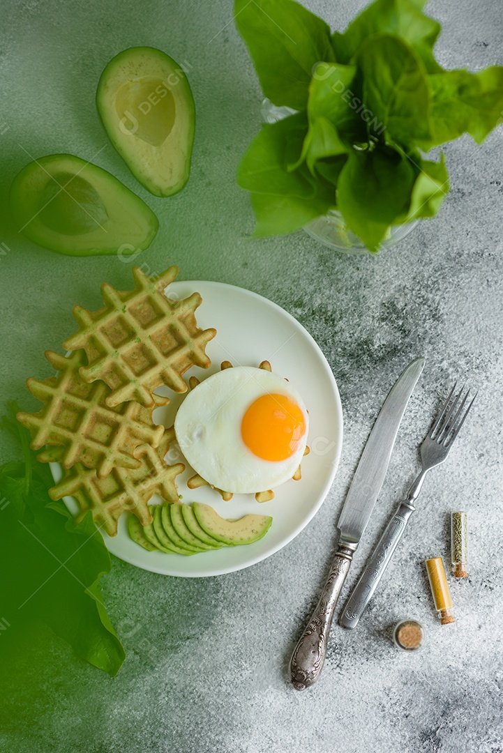 Pequeno-almoço fresco, delicioso e nutritivo com waffles com espinafre, ovo frito e pedaços de abacate