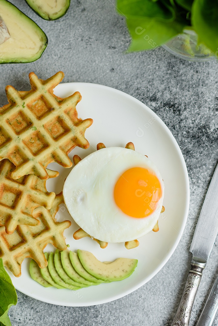 Pequeno-almoço fresco, delicioso e nutritivo com waffles com espinafre, ovo frito e pedaços de abacate