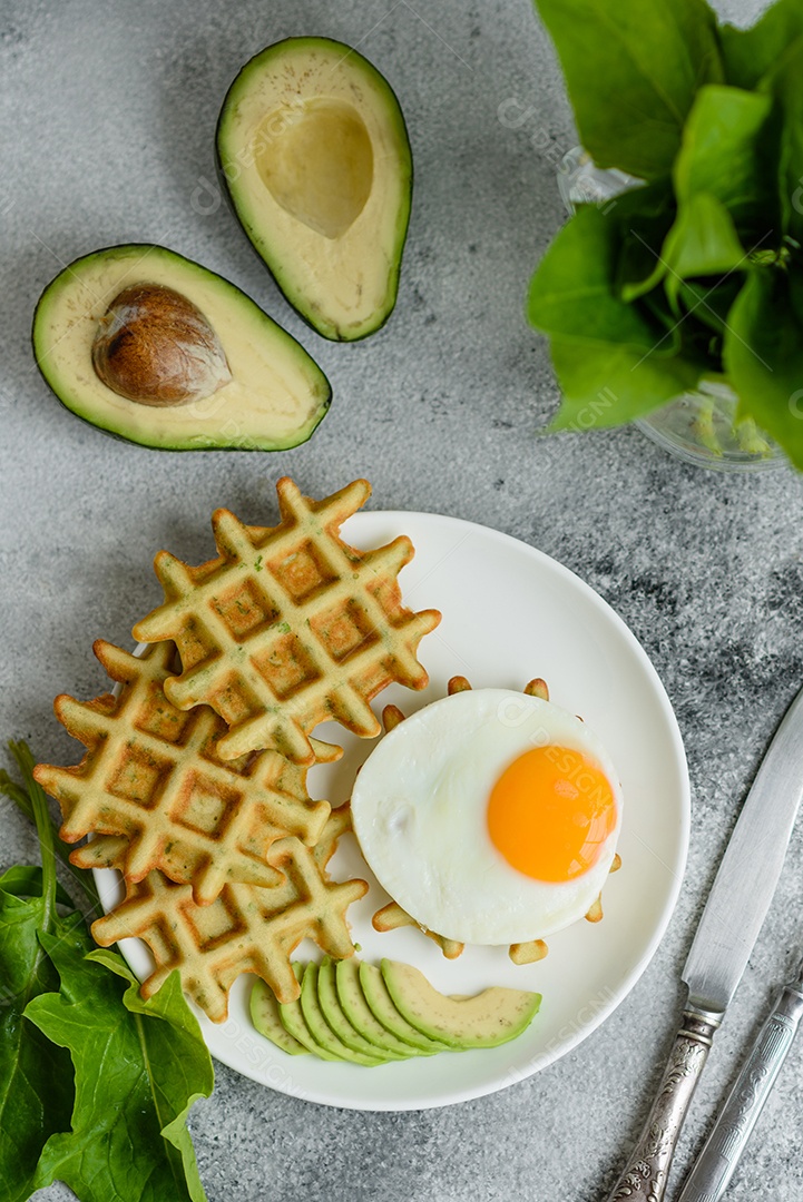 Pequeno-almoço fresco, delicioso e nutritivo com waffles com espinafre, ovo frito e pedaços de abacate