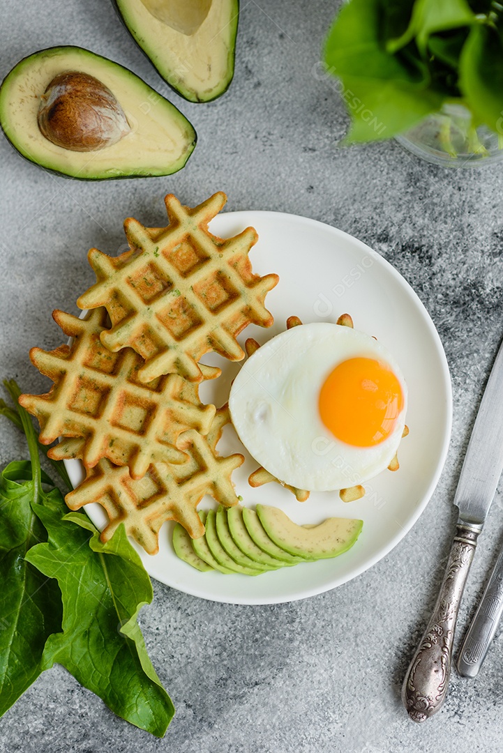 Pequeno-almoço fresco, delicioso e nutritivo com waffles com espinafre, ovo frito e pedaços de abacate
