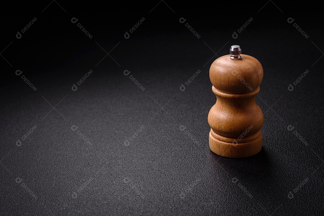 Lindo pimenteiro de madeira ou saleiro com um moinho sobre um fundo escuro e texturizado