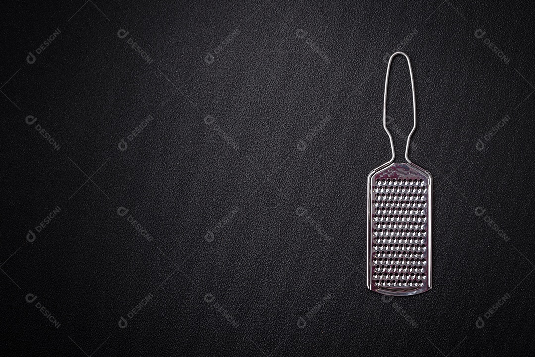 Lindo ralador de cozinha de metal pequeno com alça em um fundo escuro e texturizado