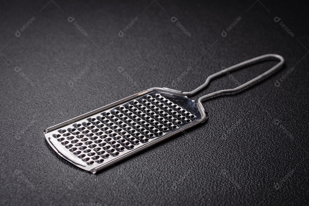 Lindo ralador de cozinha de metal pequeno com alça em um fundo escuro e texturizado