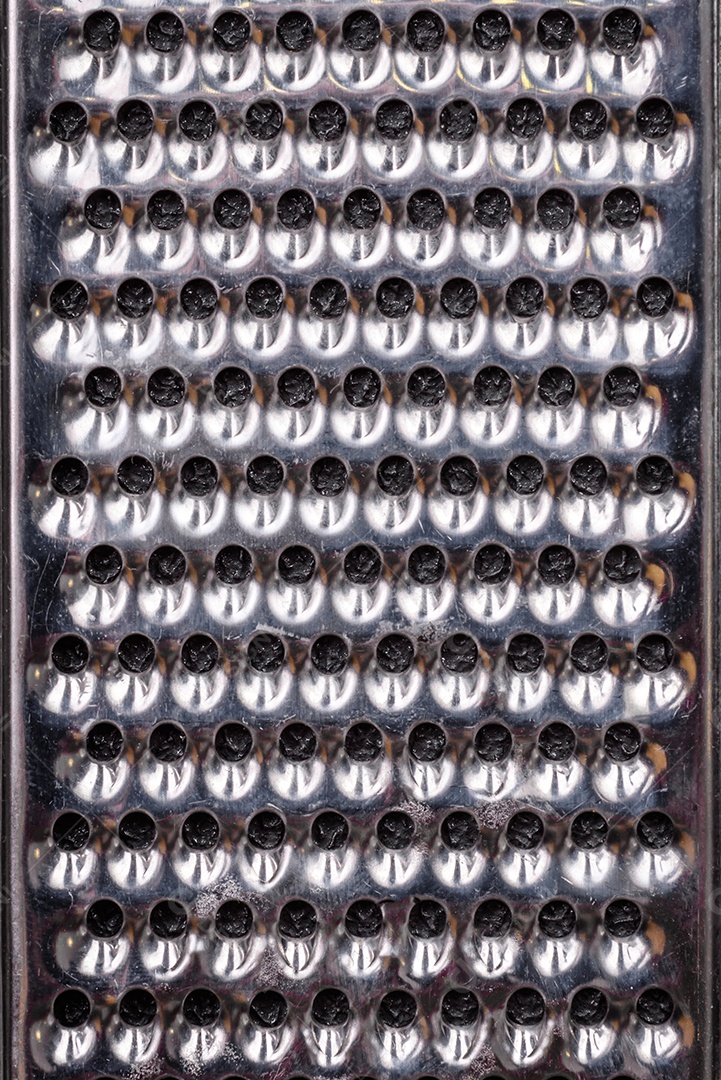 Lindo ralador de cozinha de metal pequeno com alça em um fundo escuro e texturizado