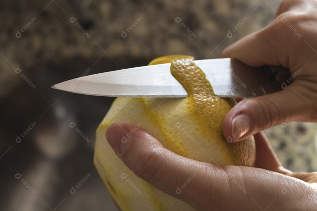 Mãos femininas cortando laranja na cozinha