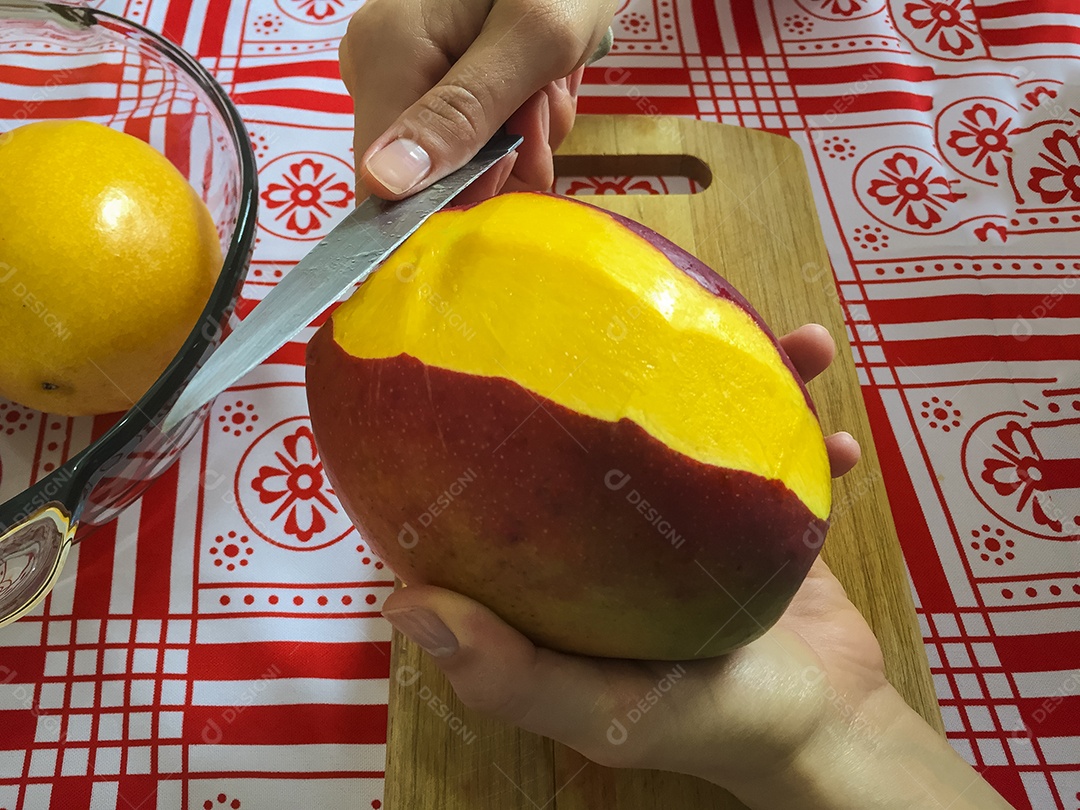 Mãos femininas cortando manga em pequenas fatias