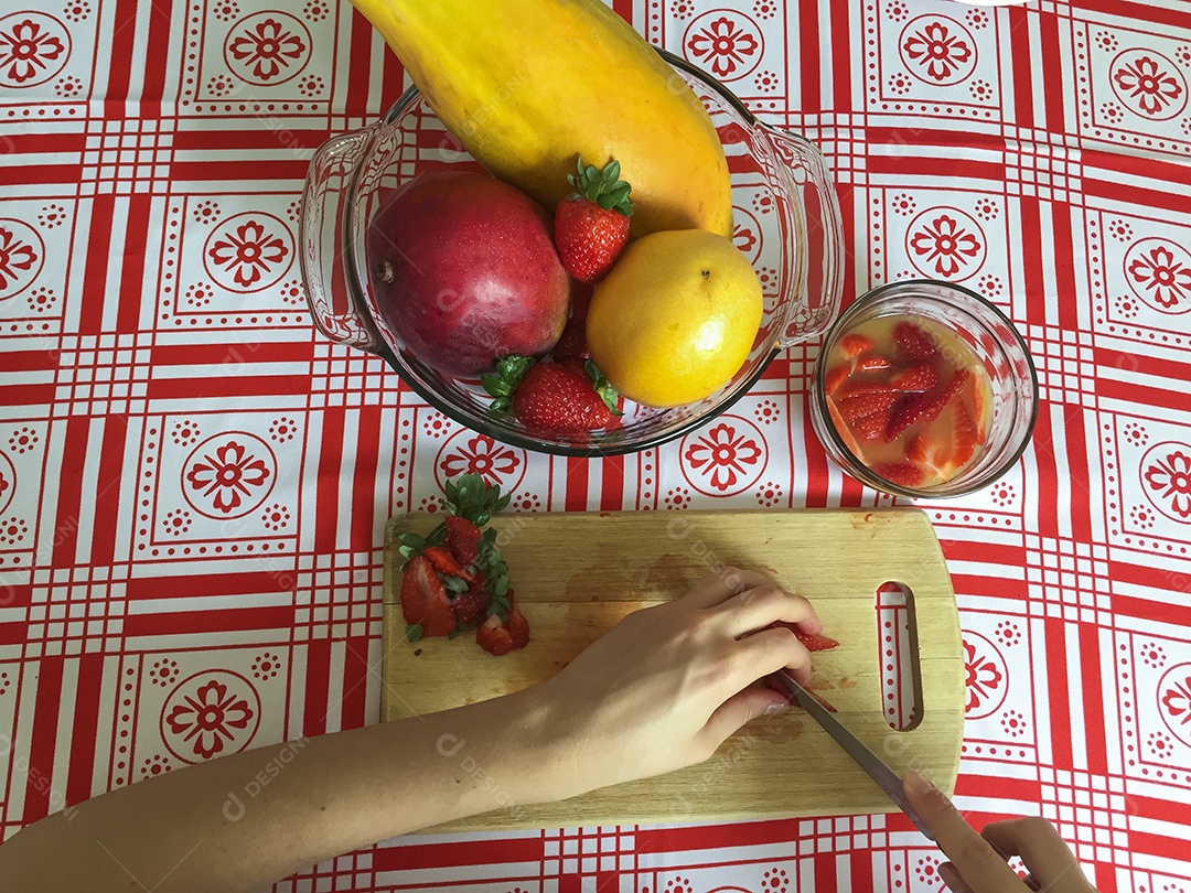 Mãos femininas cortando manga em pequenas fatias