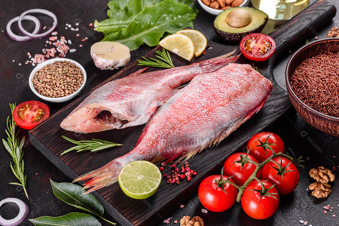 Filé cru de perca do mar vermelho preparado para assar com especiarias e ervas em um fundo escuro