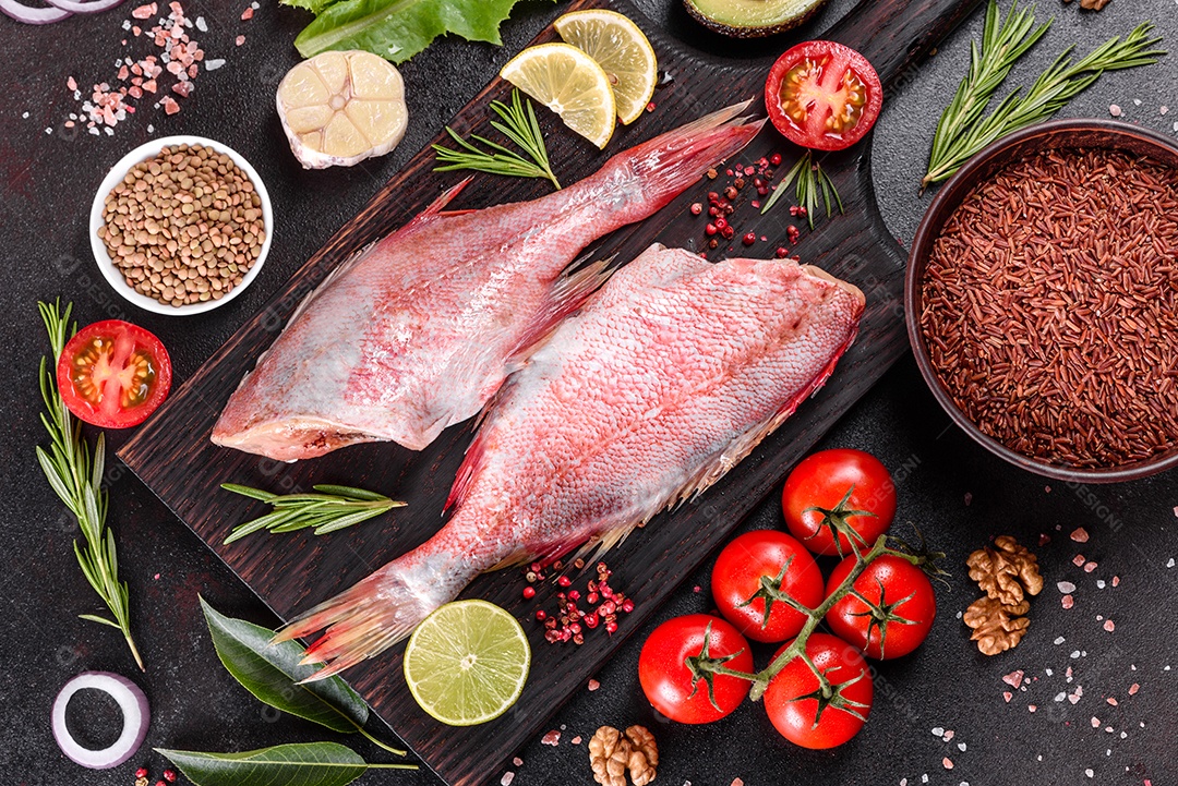 Filé cru de perca do mar vermelho preparado para assar com especiarias e ervas em um fundo escuro