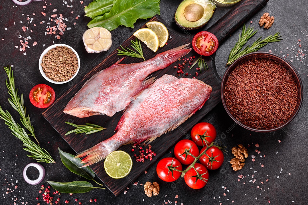 Filé cru de perca do mar vermelho preparado para assar com especiarias e ervas em um fundo escuro