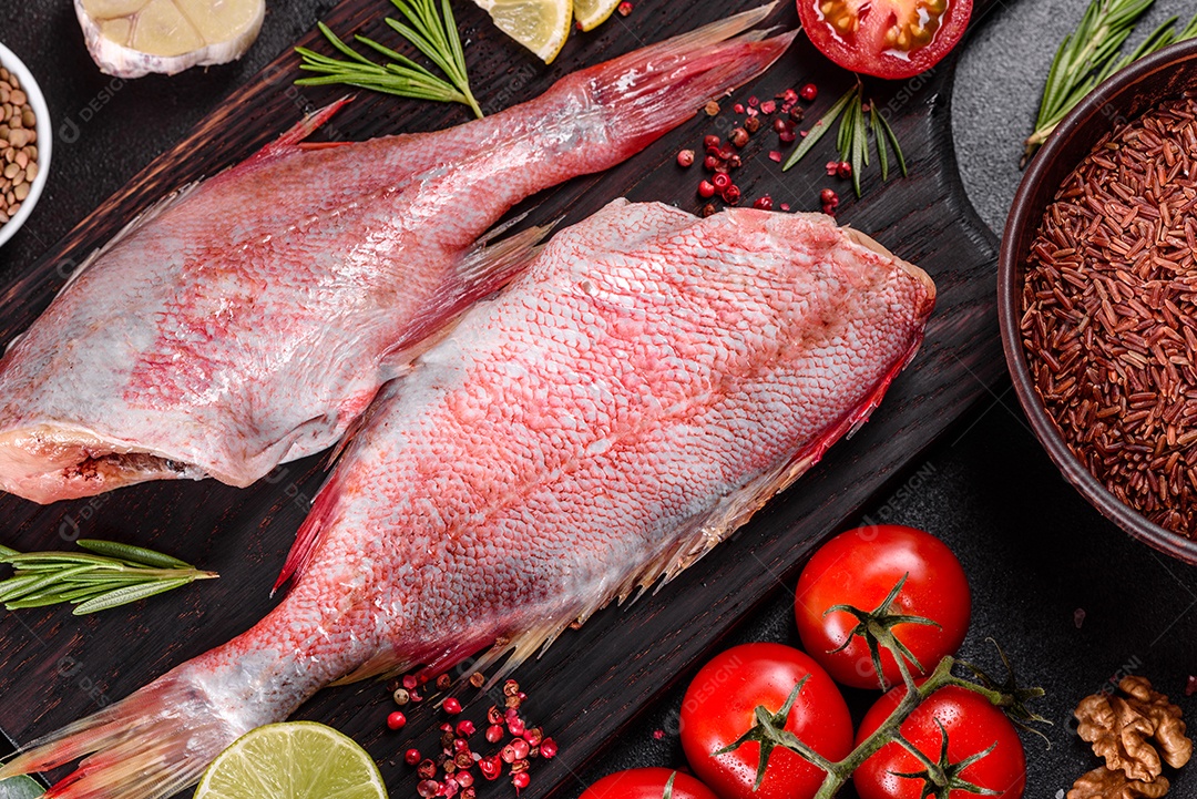 Filé cru de perca do mar vermelho preparado para assar com especiarias e ervas em um fundo escuro