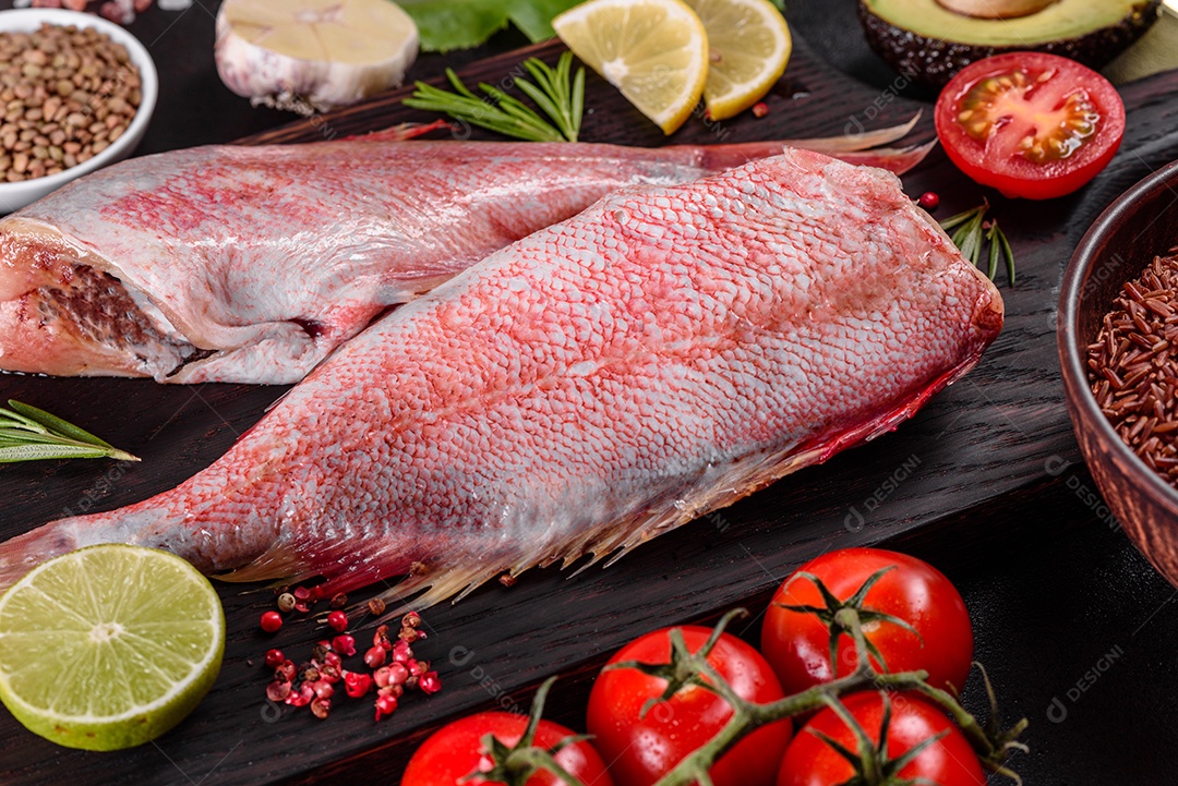 Filé cru de perca do mar vermelho preparado para assar com especiarias e ervas em um fundo escuro