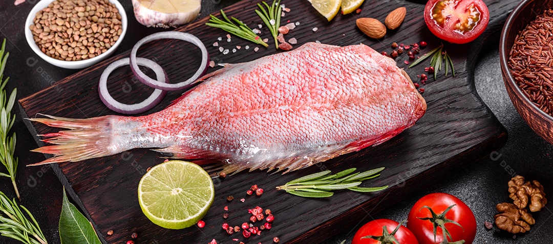 Filé cru de perca do mar vermelho preparado para assar com especiarias e ervas em um fundo escuro