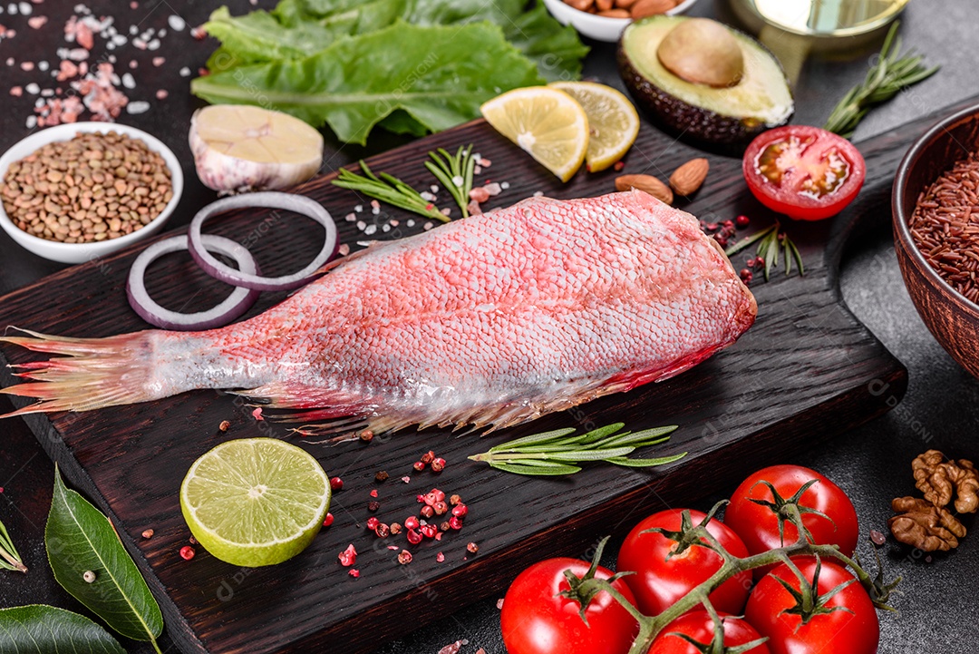 Filé cru de perca do mar vermelho preparado para assar com especiarias e ervas em um fundo escuro