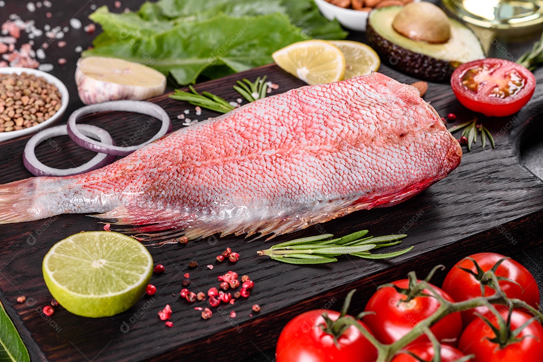 Filé cru de perca do mar vermelho preparado para assar com especiarias e ervas em um fundo escuro
