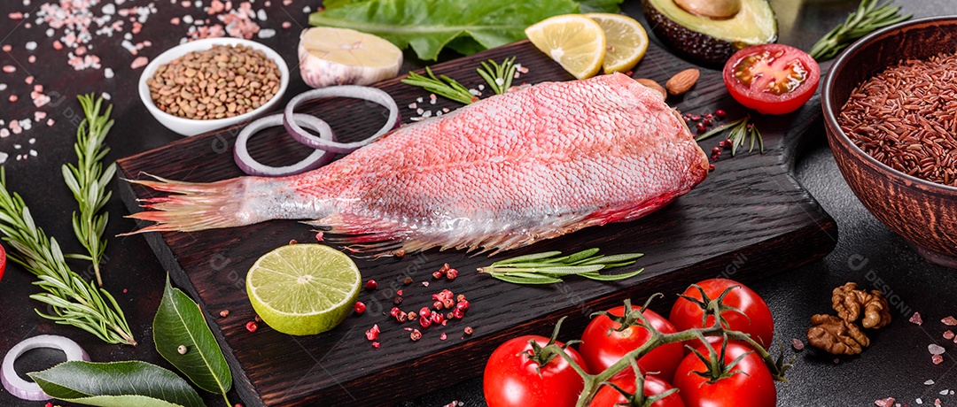 Filé cru de perca do mar vermelho preparado para assar com especiarias e ervas em um fundo escuro