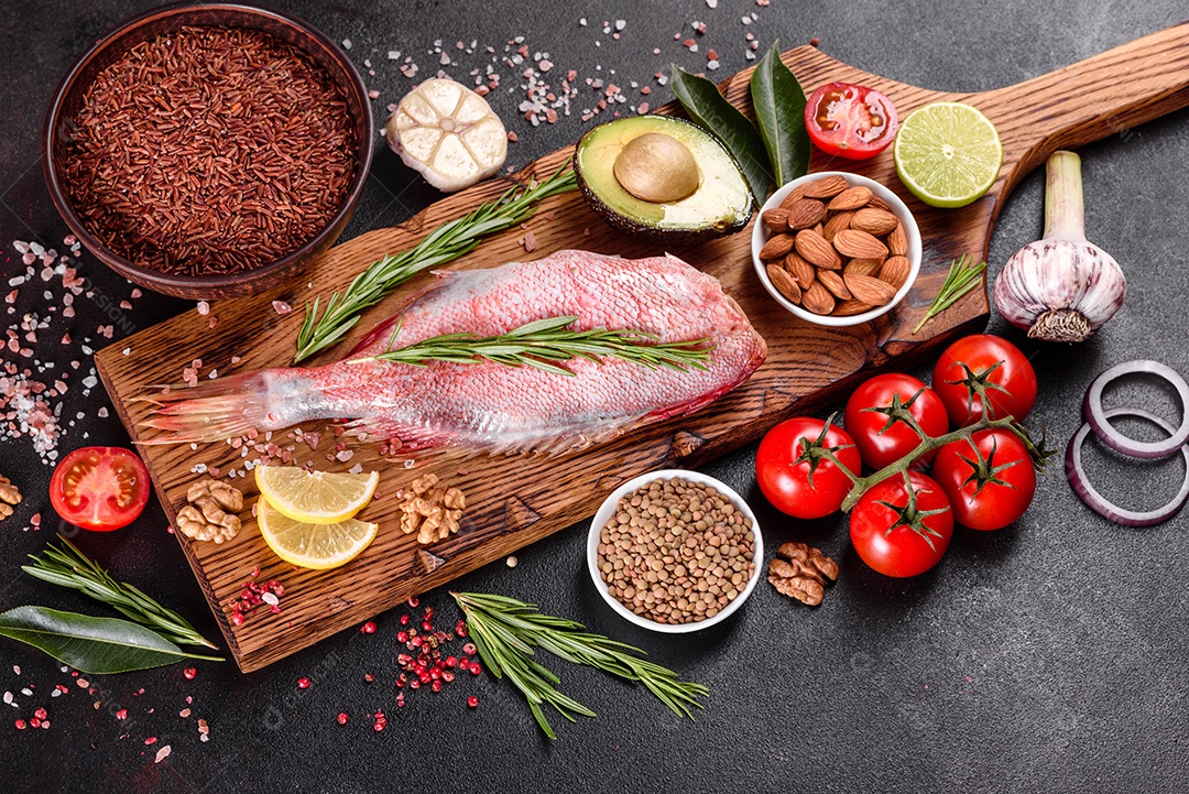 Filé cru de perca do mar vermelho preparado para assar com especiarias e ervas em um fundo escuro