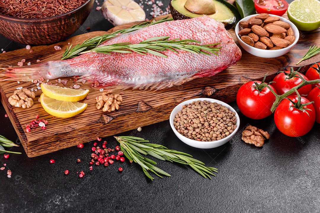 Filé cru de perca do mar vermelho preparado para assar com especiarias e ervas em um fundo escuro