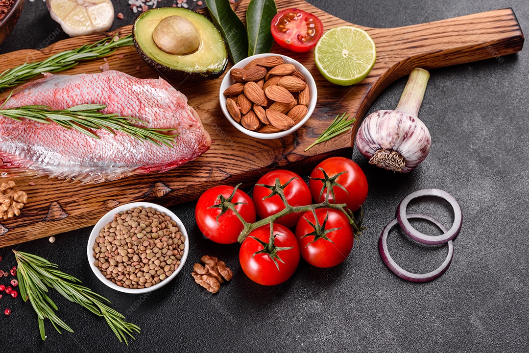 Filé cru de perca do mar vermelho preparado para assar com especiarias e ervas em um fundo escuro