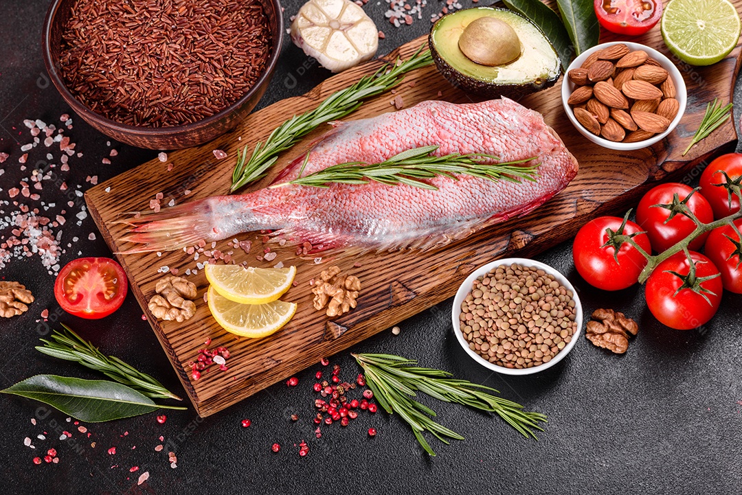 Filé cru de perca do mar vermelho preparado para assar com especiarias e ervas em um fundo escuro