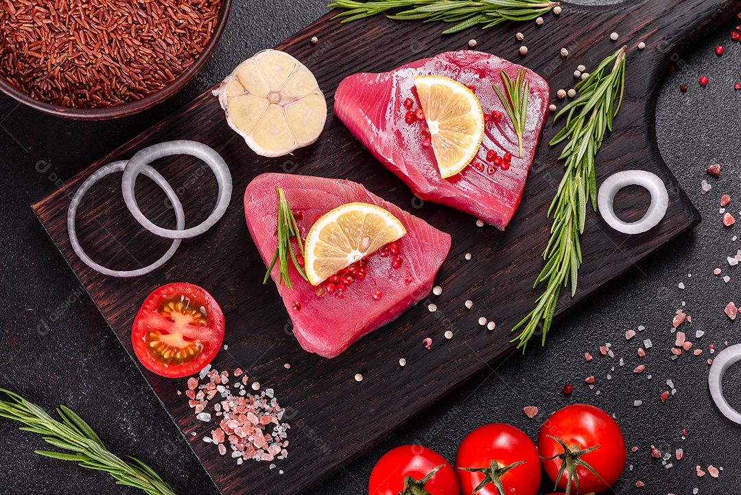 Bifes de filé de atum fresco com especiarias e ervas sobre fundo preto. Preparando atum para assar