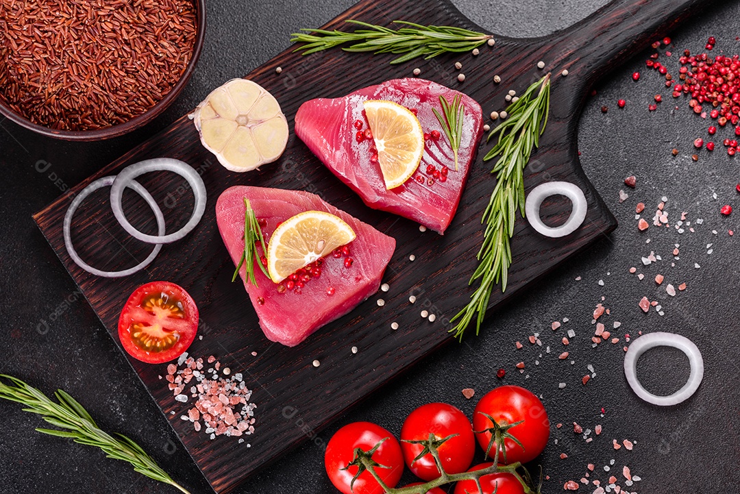 Bifes de filé de atum fresco com especiarias e ervas sobre fundo preto. Preparando atum para assar