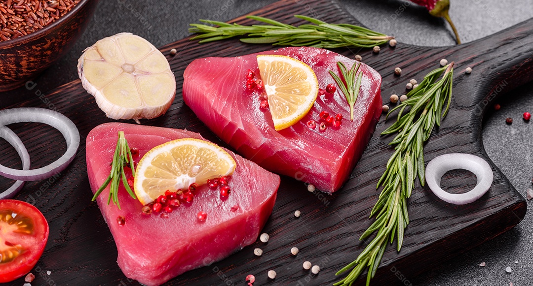 Bifes de filé de atum fresco com especiarias e ervas sobre fundo preto. Preparando atum para assar