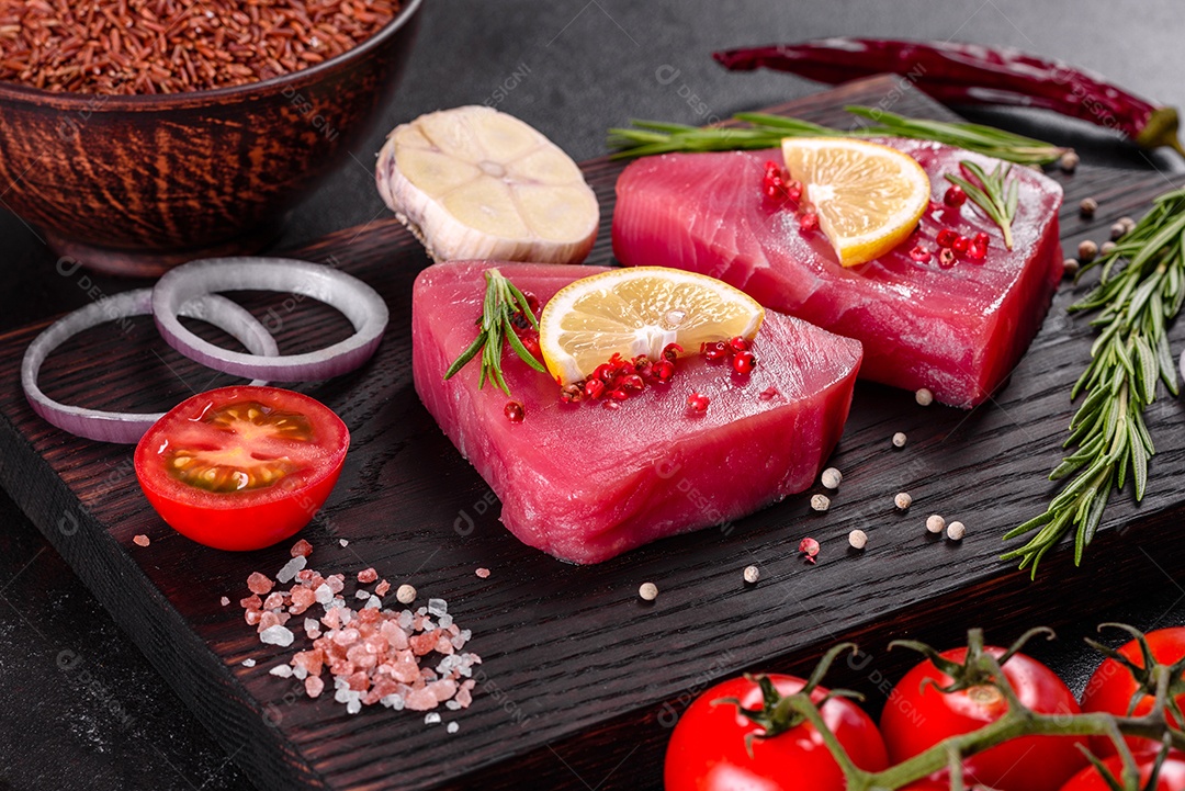 Bifes de filé de atum fresco com especiarias e ervas sobre fundo preto. Preparando atum para assar