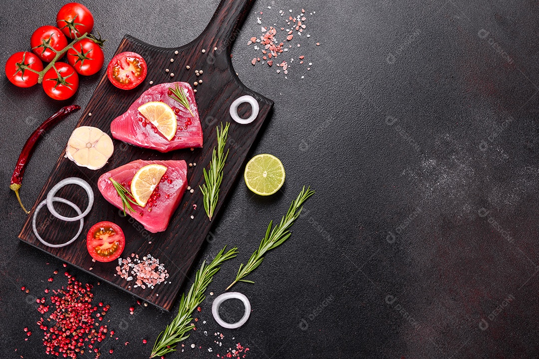 Bifes de filé de atum fresco com especiarias e ervas sobre fundo preto. Preparando atum para assar