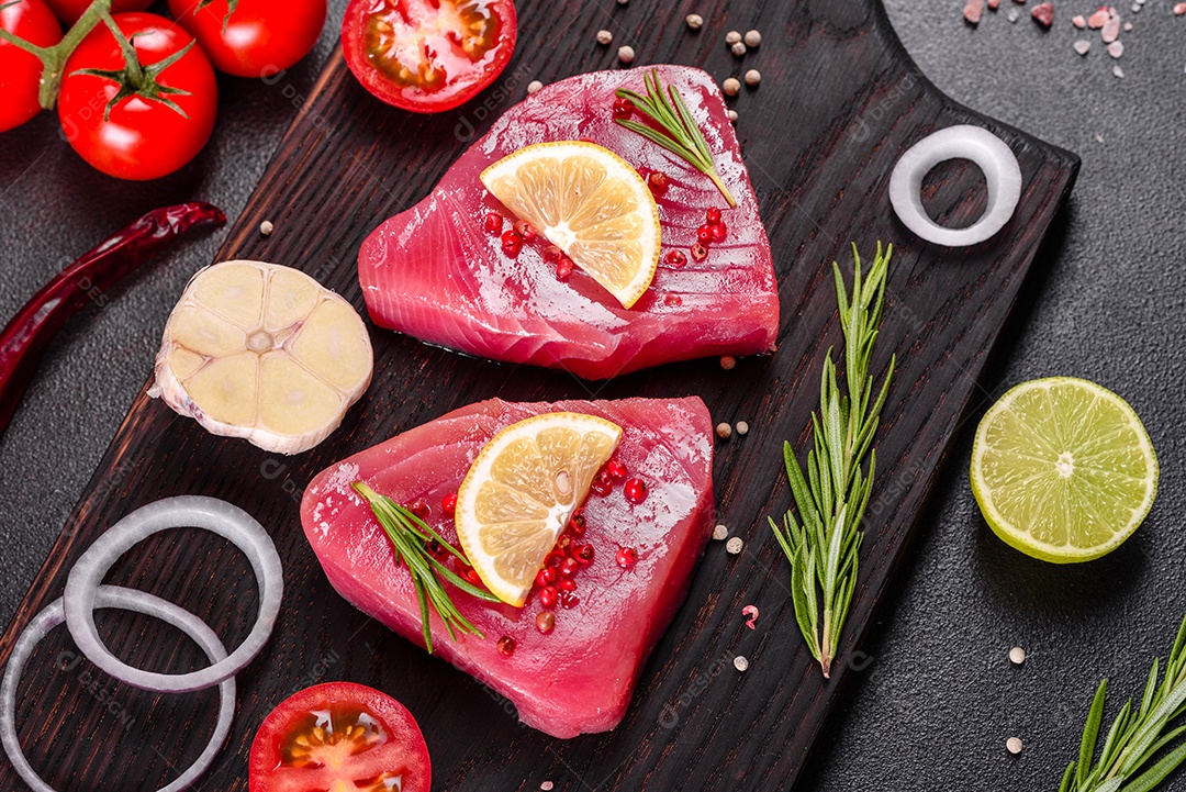 Bifes de filé de atum fresco com especiarias e ervas sobre fundo preto. Preparando atum para assar
